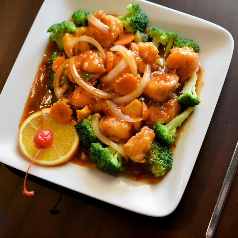 Asian Eatery's sweet and sour chicken with broccoli, onions, carrots, and an orange slice with a cherry.